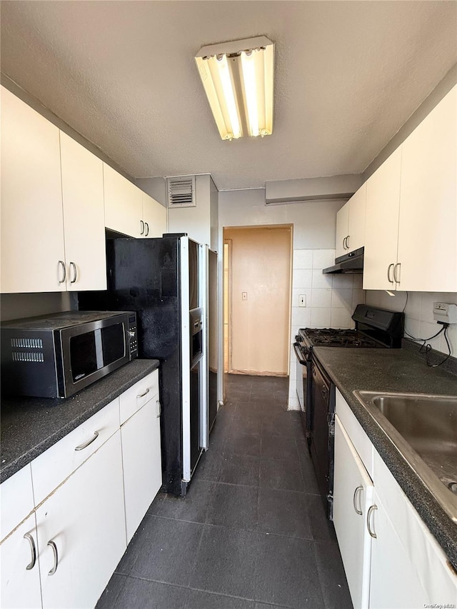 kitchen featuring black gas range, backsplash, white cabinetry, and sink