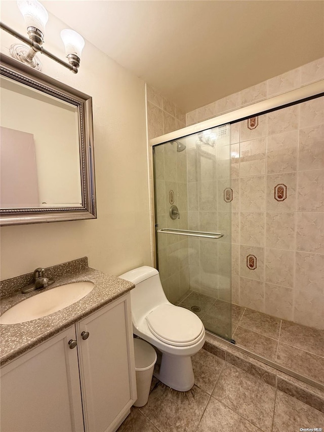 bathroom featuring tile patterned flooring, vanity, toilet, and walk in shower