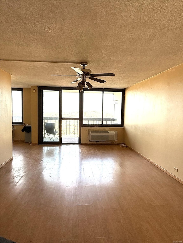 unfurnished room featuring ceiling fan, hardwood / wood-style flooring, a textured ceiling, and a wall mounted AC