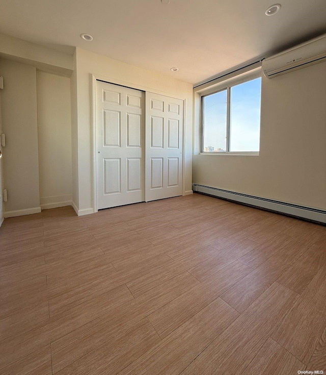 unfurnished bedroom featuring light wood-type flooring, a closet, an AC wall unit, and baseboard heating