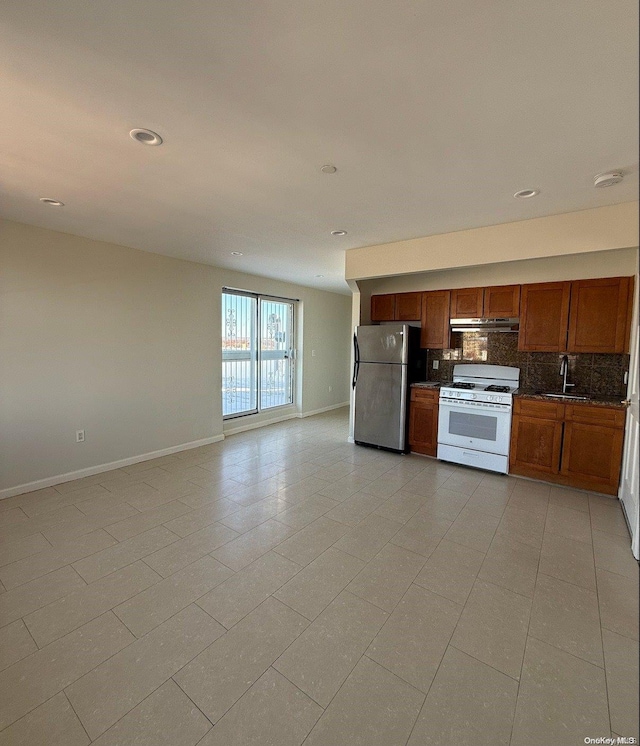 kitchen featuring sink, stainless steel fridge, white range with gas cooktop, decorative backsplash, and light tile patterned floors