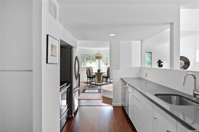 kitchen with range, sink, dark hardwood / wood-style floors, stainless steel fridge, and white cabinetry