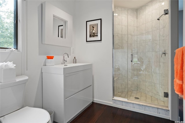 bathroom with toilet, vanity, a shower with shower door, and wood-type flooring