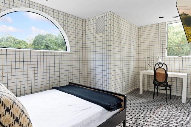 bedroom with multiple windows and tile walls