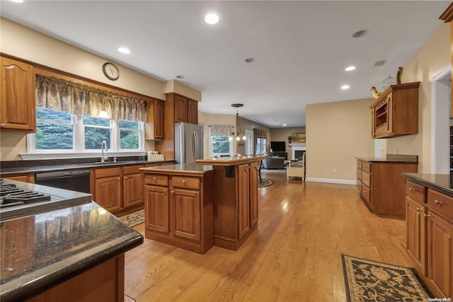 kitchen featuring a center island, sink, black dishwasher, stainless steel fridge, and light hardwood / wood-style floors