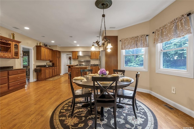 dining room with light hardwood / wood-style floors and an inviting chandelier