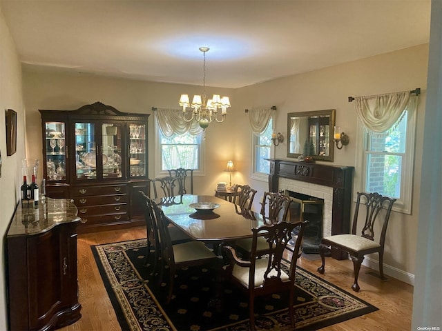 dining room with hardwood / wood-style flooring, a fireplace, and a chandelier