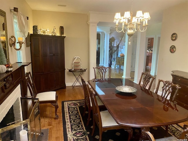 dining space featuring hardwood / wood-style floors, a notable chandelier, and decorative columns