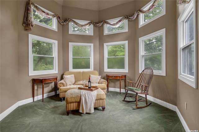 sitting room featuring a high ceiling, dark carpet, and plenty of natural light