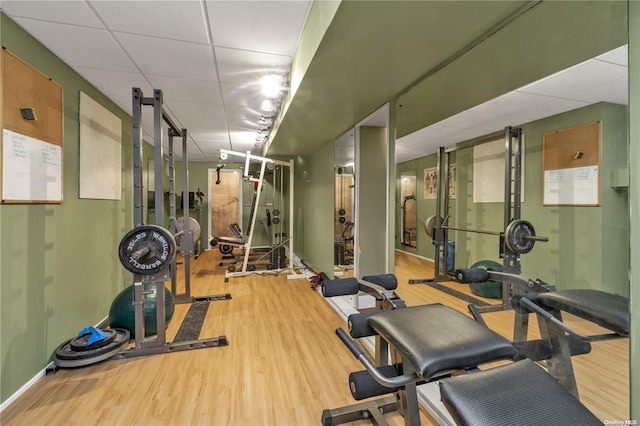 workout room with a paneled ceiling and wood-type flooring