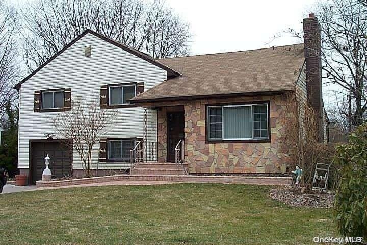 tri-level home with a garage and a front lawn