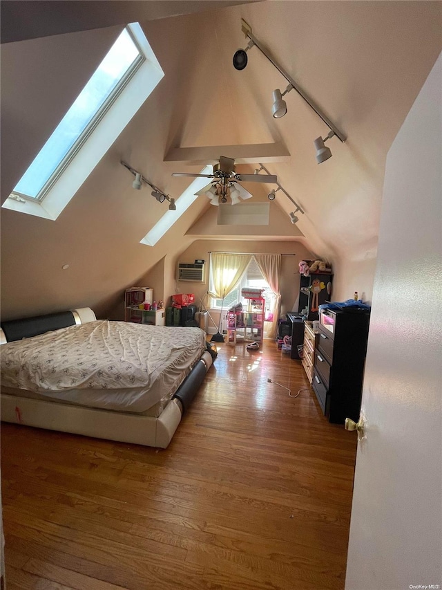 bedroom featuring lofted ceiling with skylight, rail lighting, dark wood-type flooring, and ceiling fan