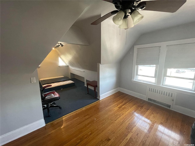 unfurnished office featuring radiator, ceiling fan, hardwood / wood-style floors, and lofted ceiling