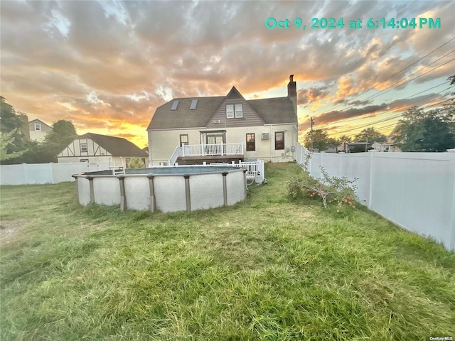 back house at dusk with a swimming pool side deck and a lawn