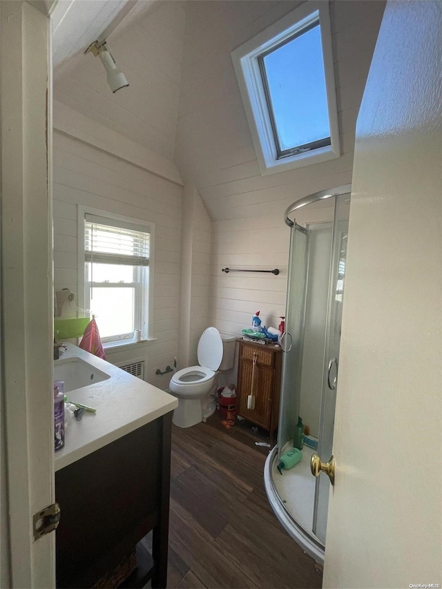 bathroom featuring vanity, lofted ceiling with skylight, a shower with door, wooden walls, and hardwood / wood-style floors