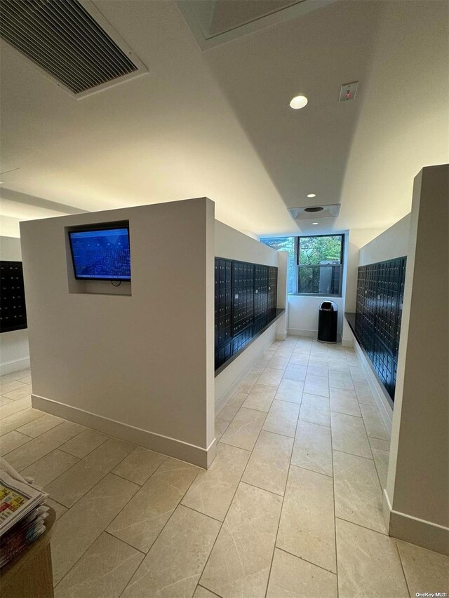 corridor featuring light tile patterned floors and a mail area