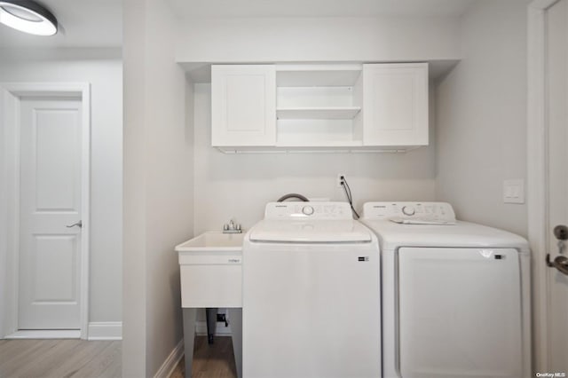 laundry room with cabinets, light hardwood / wood-style floors, and washer and dryer