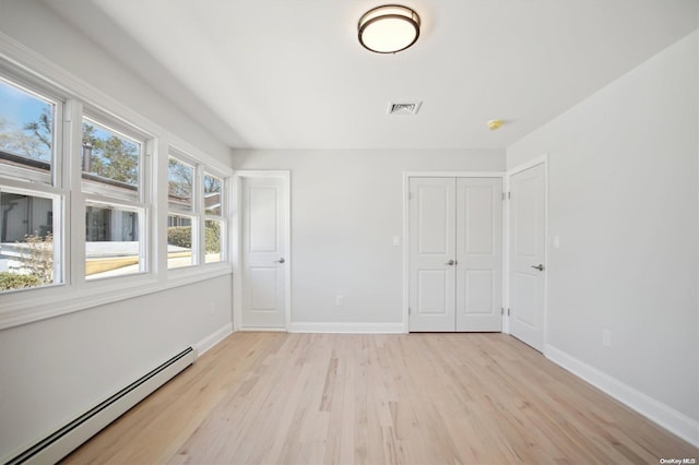 unfurnished room featuring light wood-type flooring and a baseboard heating unit