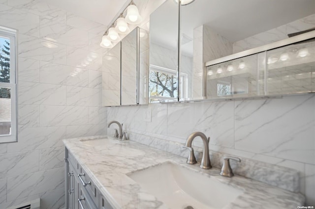 bathroom with plenty of natural light, vanity, a shower with shower door, and tile walls