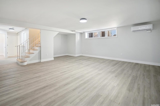 basement featuring an AC wall unit and light hardwood / wood-style floors