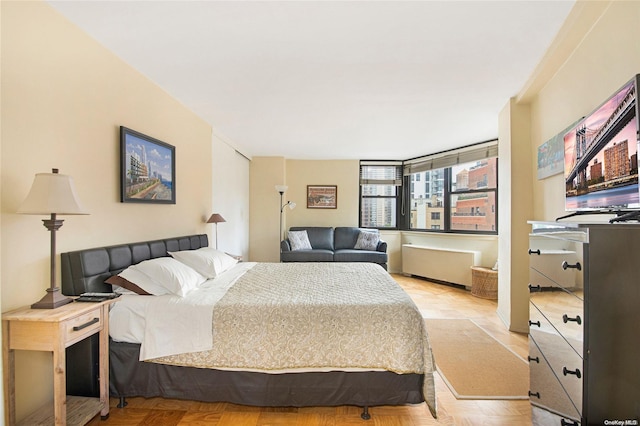 bedroom with radiator heating unit and light parquet floors