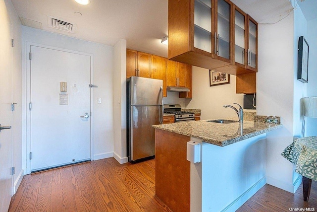 kitchen featuring appliances with stainless steel finishes, sink, dark hardwood / wood-style floors, kitchen peninsula, and stone counters