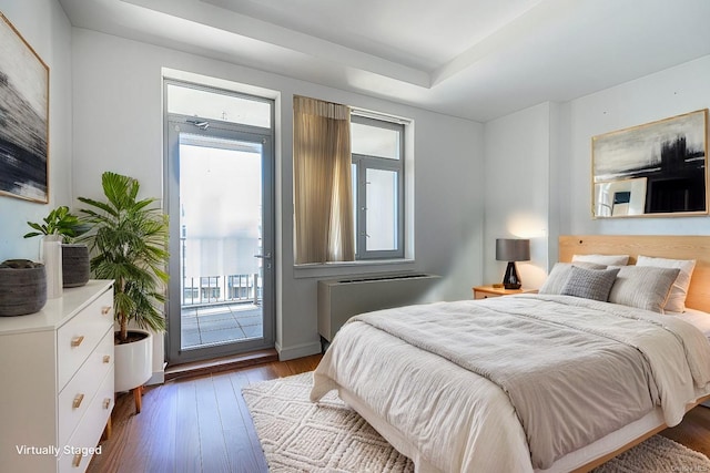 bedroom featuring hardwood / wood-style flooring, access to exterior, multiple windows, and radiator heating unit