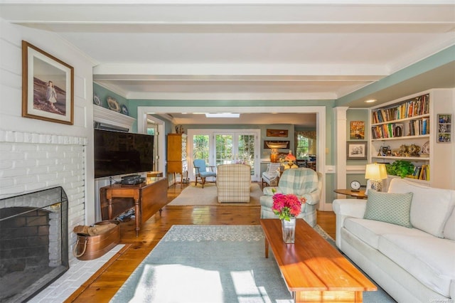 living room featuring beamed ceiling, wood-type flooring, and a fireplace