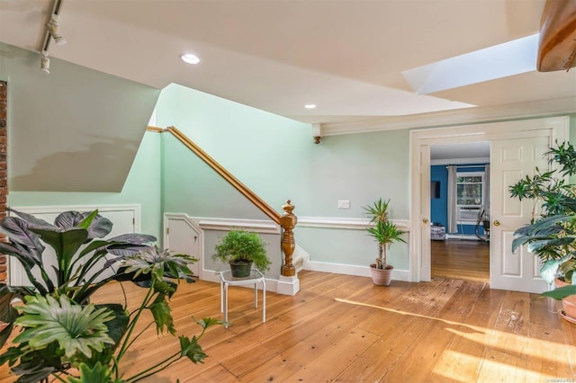 interior space with a skylight, track lighting, and hardwood / wood-style flooring