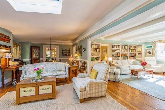 living room with built in shelves, light hardwood / wood-style flooring, ornamental molding, and a notable chandelier