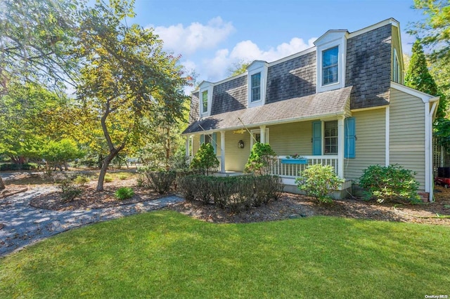 new england style home featuring covered porch and a front lawn