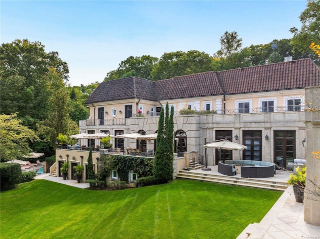 back of property featuring a lawn and a balcony