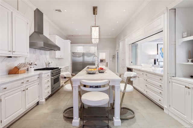 kitchen featuring white cabinets, hanging light fixtures, high quality appliances, and wall chimney range hood