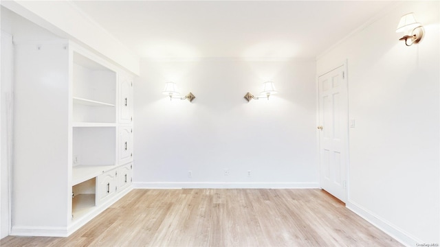 spare room with ornamental molding and light wood-type flooring