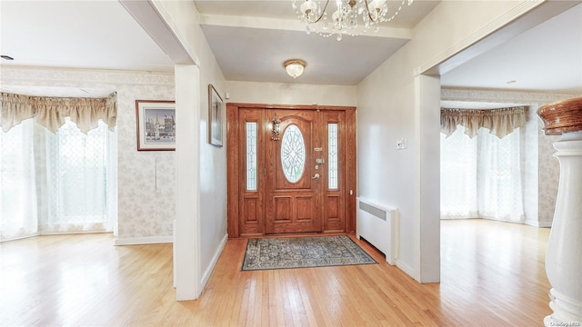 entryway with an inviting chandelier, radiator heating unit, and light wood-type flooring