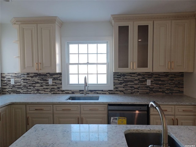 kitchen featuring stainless steel dishwasher, backsplash, sink, and cream cabinets