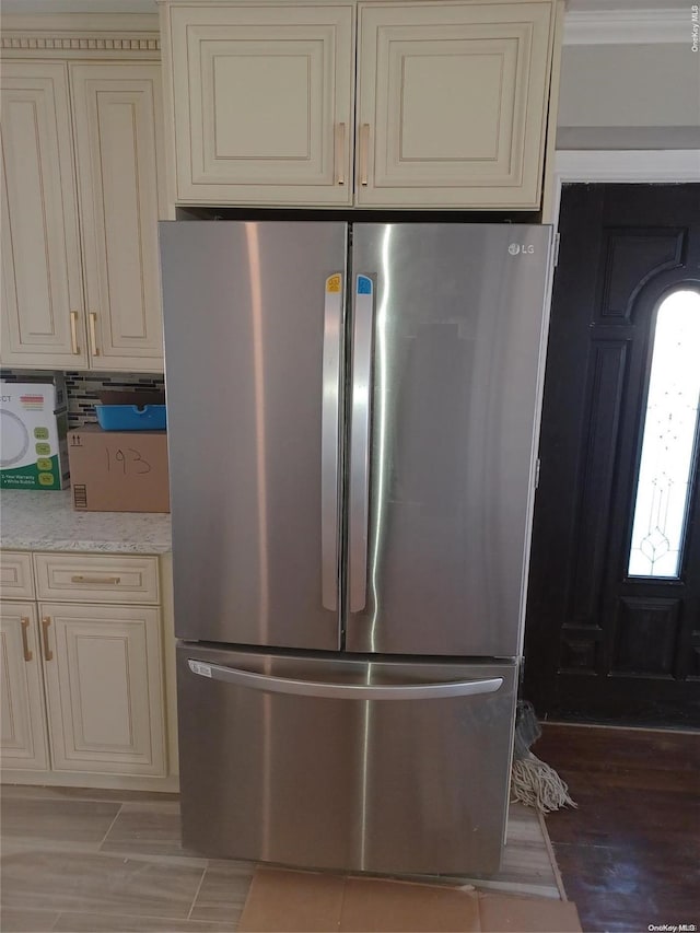 kitchen featuring hardwood / wood-style floors, stainless steel refrigerator, and cream cabinets