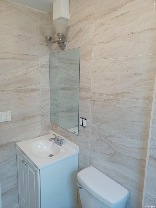 bathroom with vanity, toilet, and tile walls