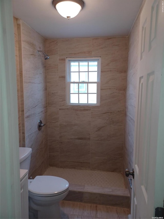 bathroom featuring a tile shower, vanity, and toilet