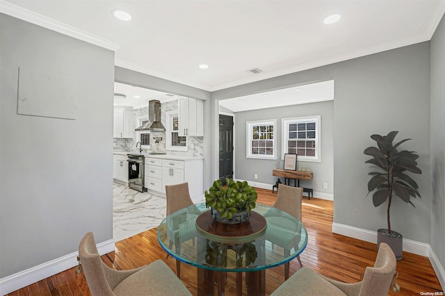 dining room with light hardwood / wood-style floors and ornamental molding