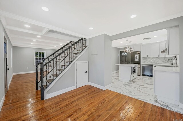 interior space with beam ceiling, sink, wood-type flooring, and ornamental molding