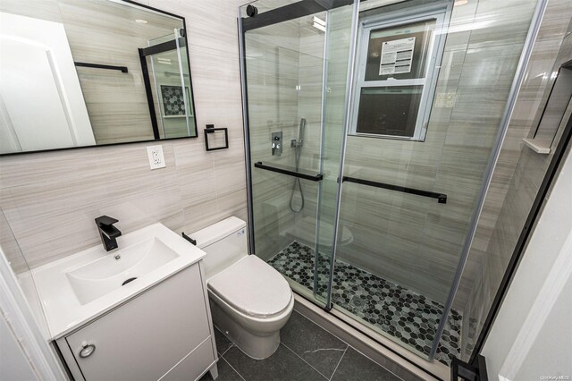 bathroom featuring tile patterned floors, an enclosed shower, toilet, vanity, and tile walls