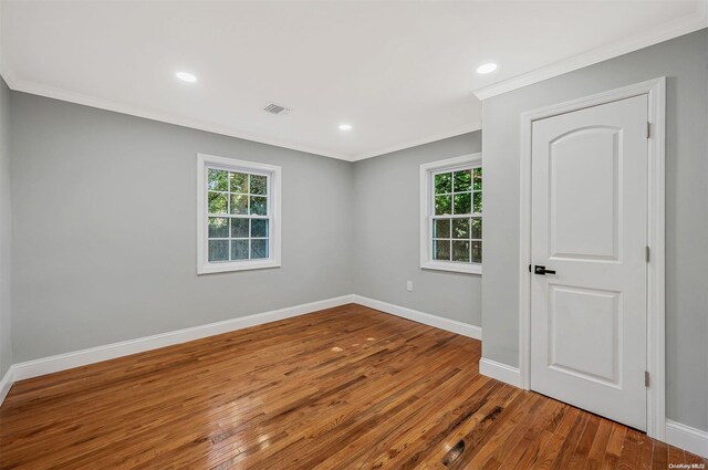 spare room with crown molding, hardwood / wood-style floors, and plenty of natural light