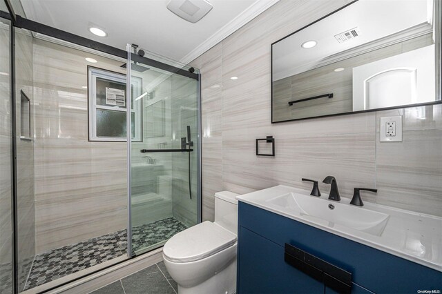 bathroom with tile patterned floors, ornamental molding, vanity, tile walls, and toilet