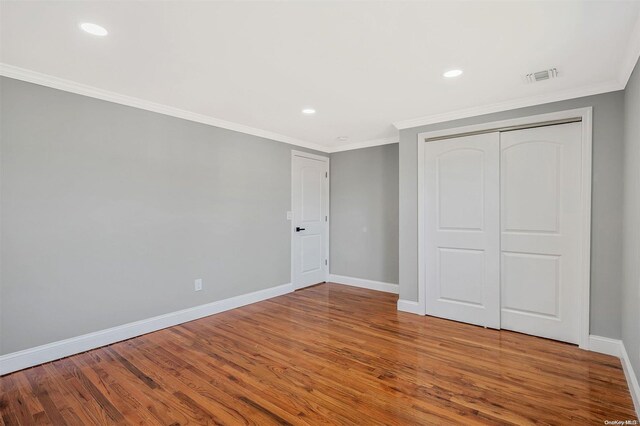 unfurnished bedroom featuring crown molding, a closet, and hardwood / wood-style flooring