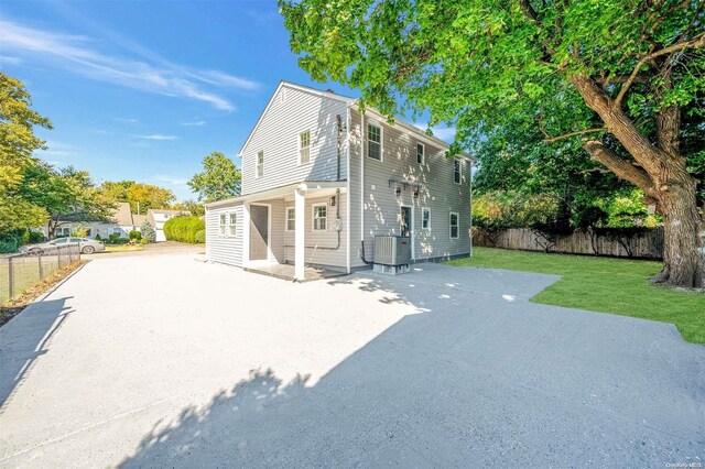 back of property with a yard, cooling unit, and a patio