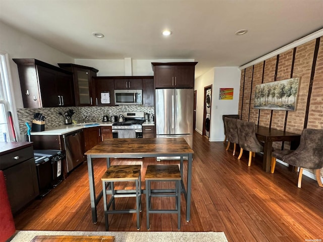 kitchen featuring appliances with stainless steel finishes, tasteful backsplash, dark brown cabinets, sink, and dark hardwood / wood-style floors