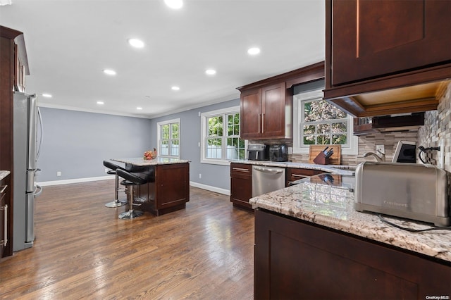 kitchen with light stone countertops, plenty of natural light, a center island, and appliances with stainless steel finishes