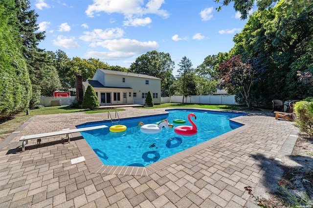 view of swimming pool with a diving board and a patio