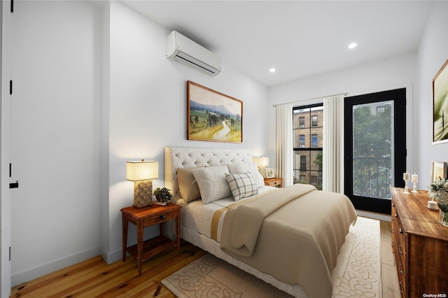 bedroom featuring light hardwood / wood-style flooring and an AC wall unit